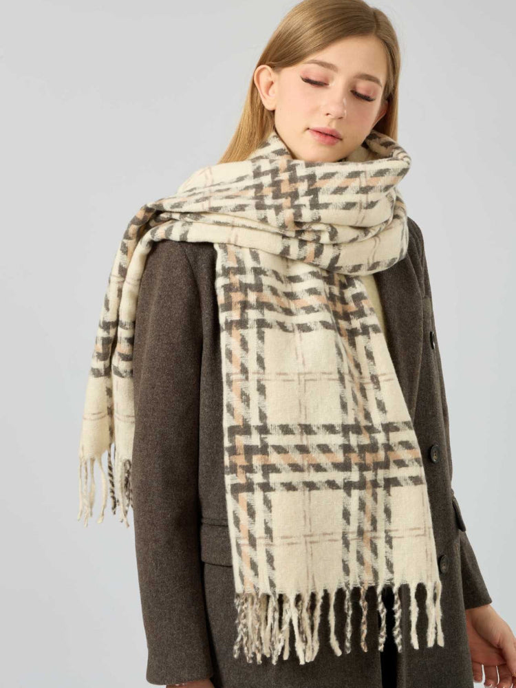 Woman wearing a cream and brown plaid scarf with fringe detail.