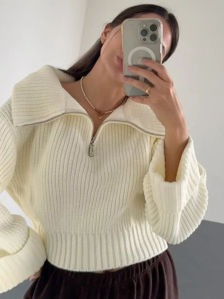 Close-up of a woman taking a selfie in a cream-colored knit sweater with a half-zip neckline.