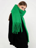 Close-up of a woman wearing a bright green brushed wool blend scarf with fringe trim.