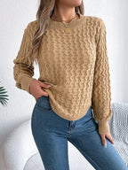 Woman wearing a tan textured knit sweater with a crew neckline and long sleeves, paired with blue jeans.