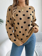 Woman wearing a tan knit sweater with a black polka dot pattern, long sleeves, and a crew neckline.