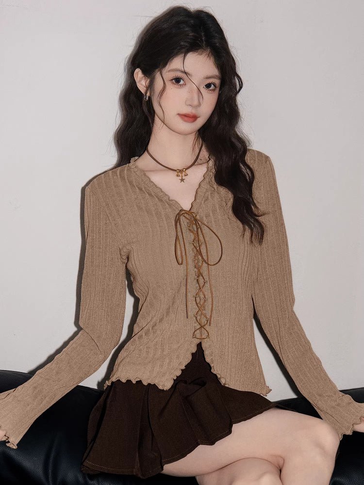 Woman sitting and wearing a tan ribbed knit long-sleeve top with a scalloped hem