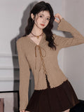 Front view of a tan ribbed knit top with a V-neck, tie-front closure, and scalloped hem.