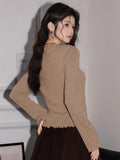 Back view of a woman in a tan ribbed knit long-sleeve top