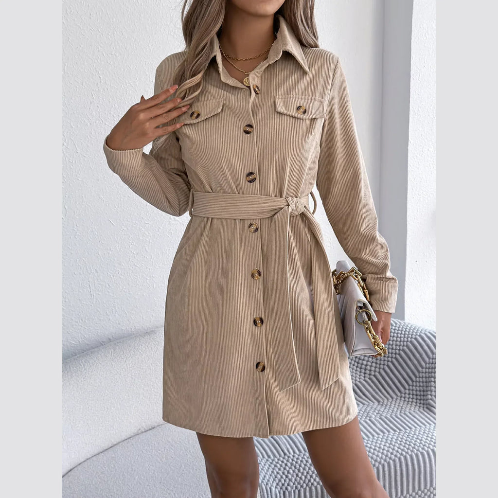 Woman wearing a beige corduroy shirt dress with a belted waist and button-down front.