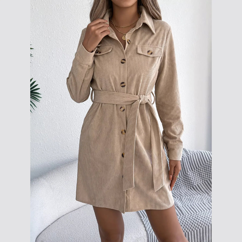 Front detail of a beige corduroy shirt dress with a pointed collar and chest pockets.