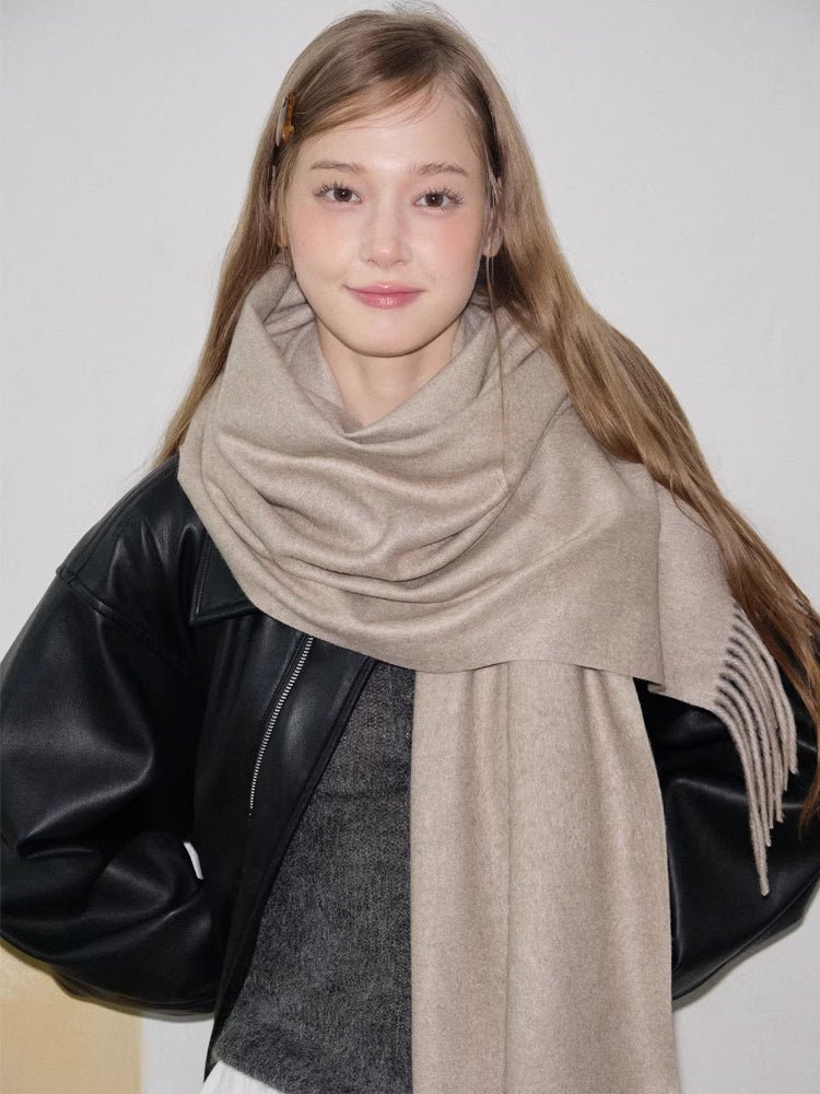 Woman wearing a beige scarf with fringe detail around her neck.