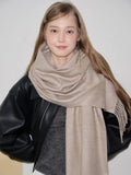 Close-up of a beige scarf with fringe detail and a brand label.