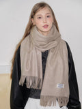 Model posing with a beige scarf draped over her shoulders.