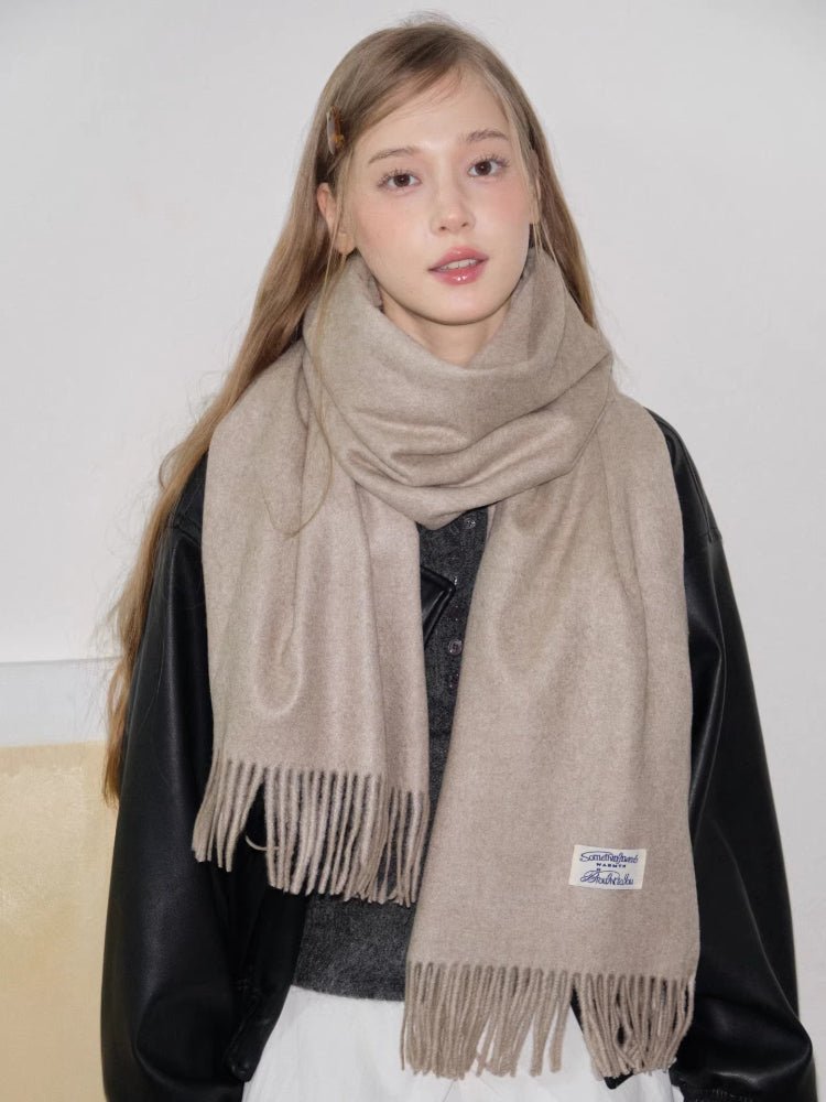 Model posing with a beige scarf draped over her shoulders.