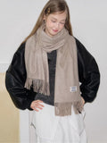 Woman styled in a beige scarf, black jacket, and white skirt.