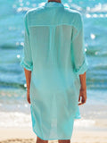 Back view of a woman wearing a light blue sheer crinkle cotton tunic on the beach