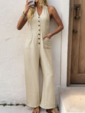 woman in beige sleeveless wide-leg jumpsuit with button-down front and halter neckline posing with a phone