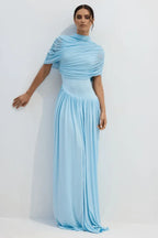 Woman wearing a light blue draped jersey maxi dress with a high neckline and pleated skirt.