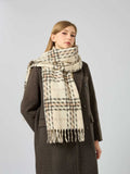 Woman wearing a cream and brown plaid scarf with fringe detail.