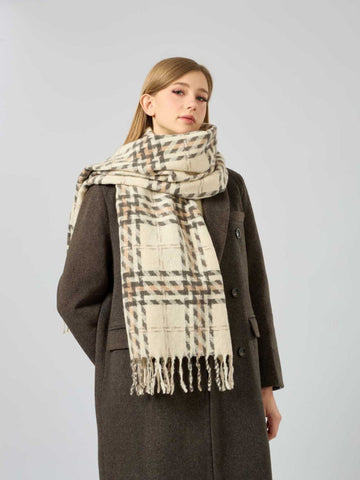 Woman wearing a cream and brown plaid scarf with fringe detail.