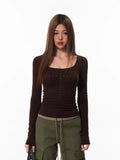 Model wearing a fitted brown long-sleeve top with embellished detailing