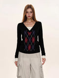 Close-up of a black argyle V-neck sweater with red and blue diamond pattern.