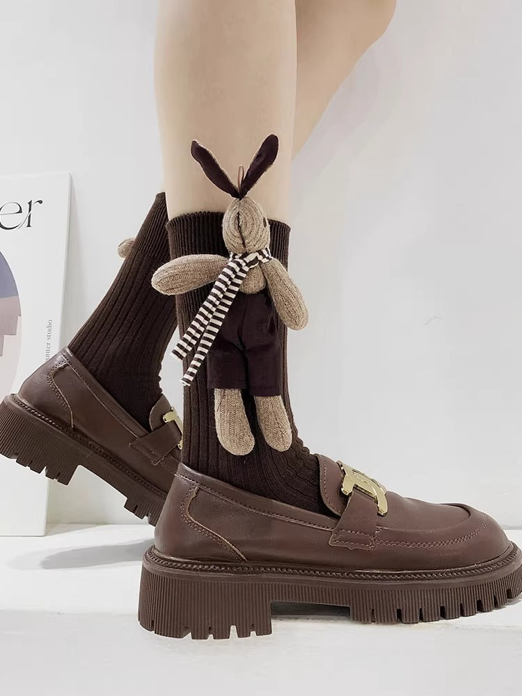 Close-up of brown crew socks with a 3D bunny embellishment and striped scarf detail.