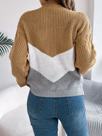 Back view of a woman in a tan, white, and grey chevron color block knit sweater