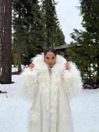 Woman in a white faux fur coat with a high collar in a snowy outdoor setting