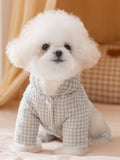 White Bichon Frise dog wearing a light green gingham hooded jumpsuit with a light green pom-pom