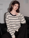 Close-up of a woman's chest area, highlighting the striped pattern and button details of the knit cardigan.