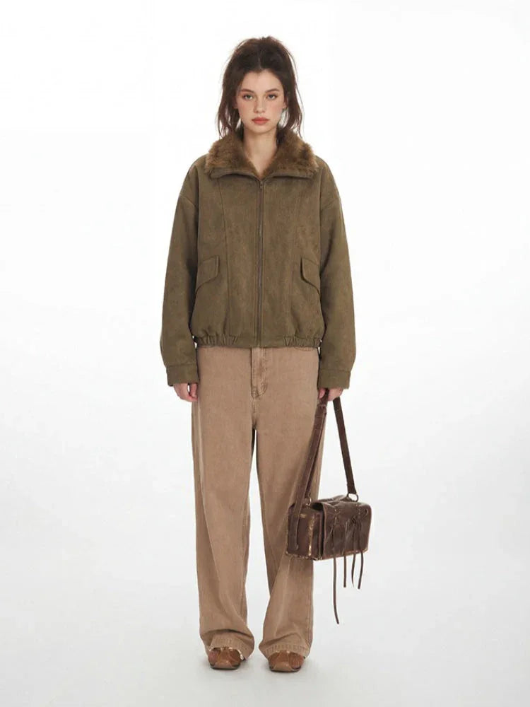 Woman wearing a green corduroy bomber jacket with a faux fur collar and tan wide-leg pants, holding a brown leather crossbody bag.