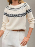 Woman wearing a cream-colored knit sweater with a black and grey Fair Isle pattern, paired with white pants and a brown belt.