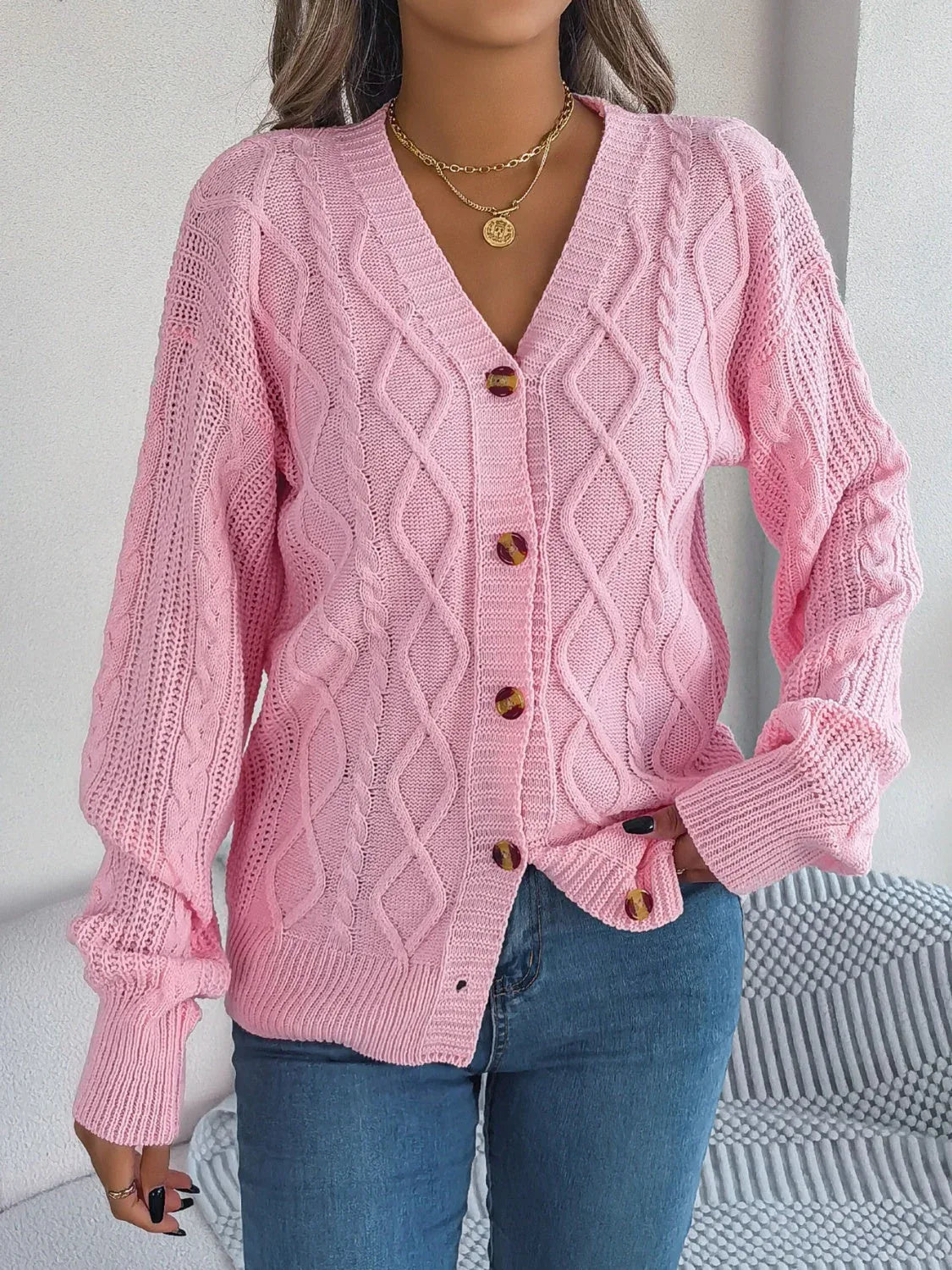 Woman wearing a pink cable knit cardigan with a v-neck and button front Main image
