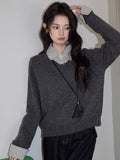 Close-up of a woman in a grey V-neck sweater and checkered shirt
