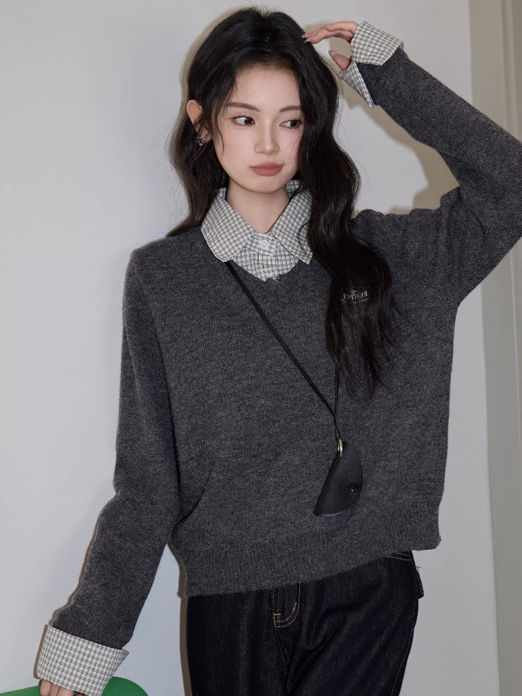 Close-up of a woman in a grey V-neck sweater and checkered shirt