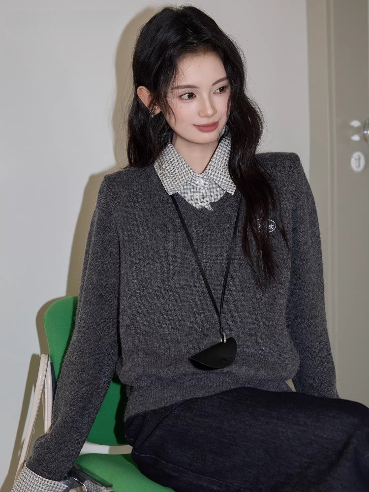 Woman wearing a grey V-neck sweater over a checkered collared shirt
