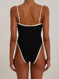 Back view of a woman in a black one-piece swimsuit with white trim.