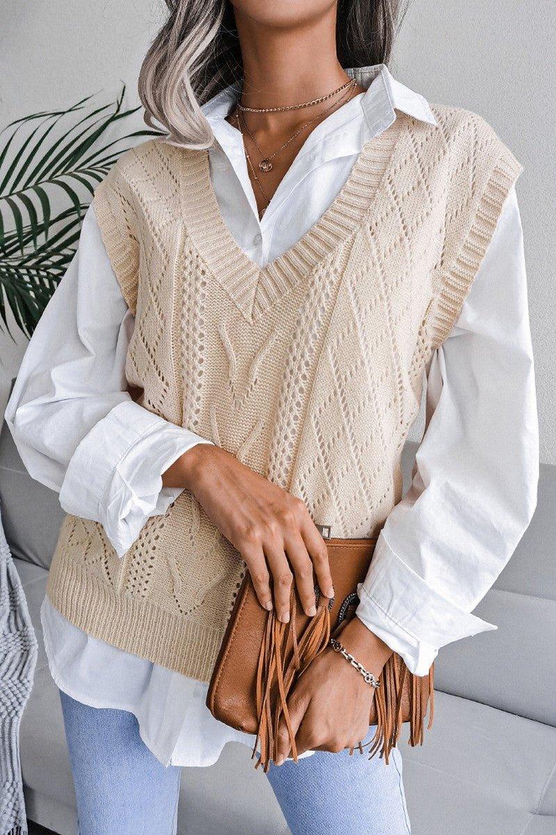 Close-up of a woman wearing a beige cable knit V-neck sleeveless sweater vest over a white collared shirt.