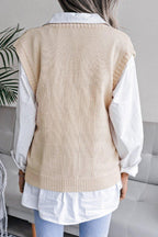Back view of a woman wearing a beige cable knit V-neck sleeveless sweater vest over a white collared shirt.