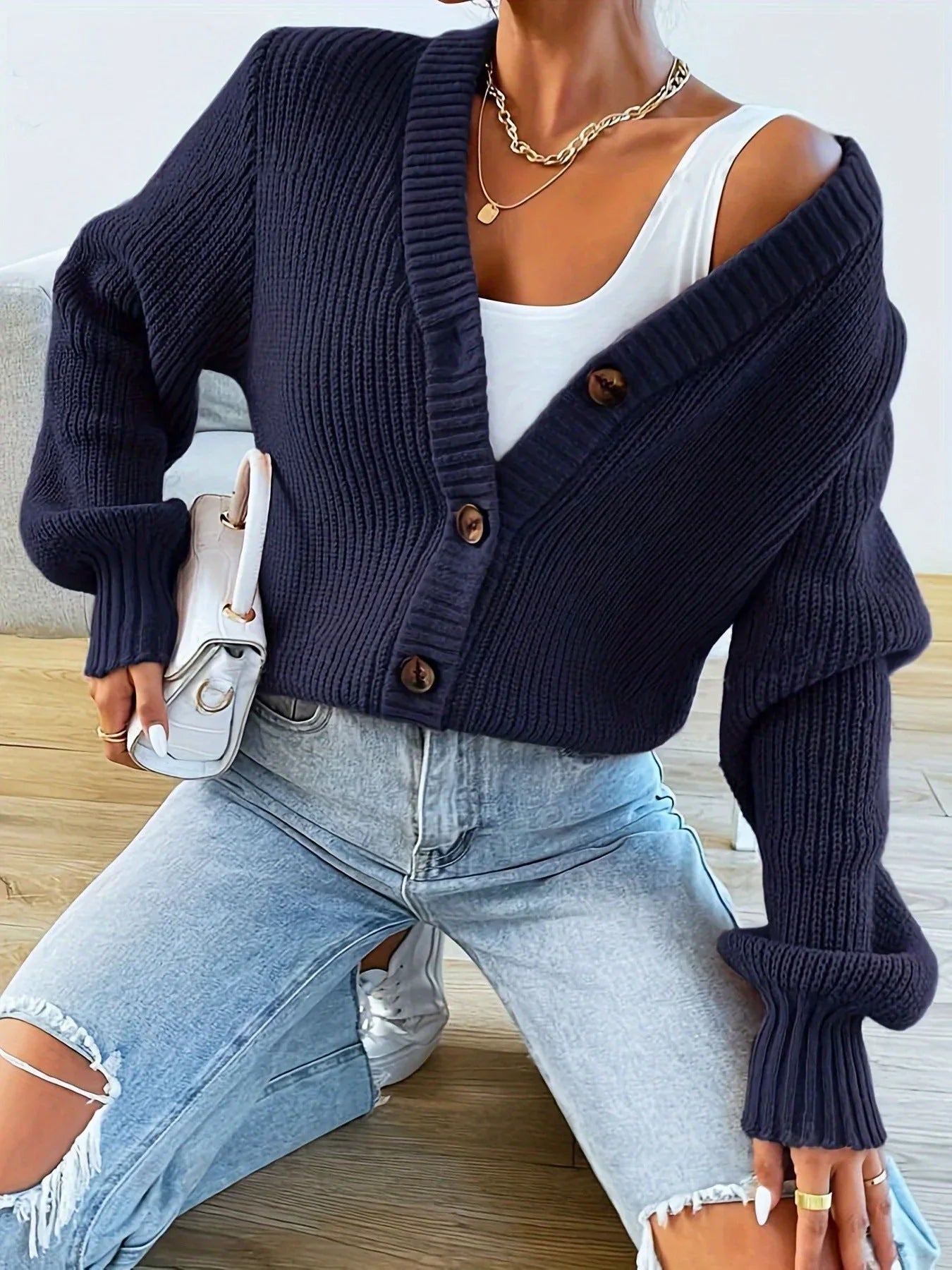 woman wearing a burgundy knit cardigan with a v-neck and button front, paired with ripped jeans