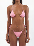 Woman wearing a cream-colored triangle bikini with black ties