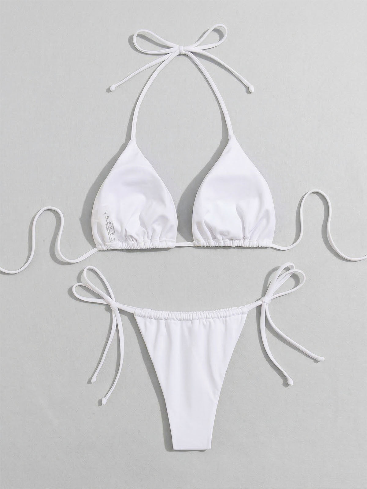 Close-up of the white bikini top featuring triangle cups and halter ties.