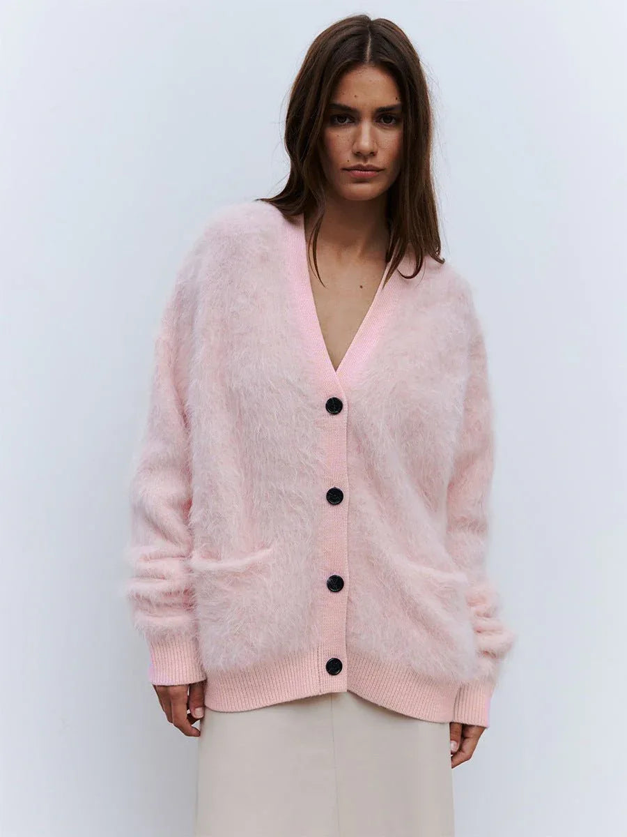Woman wearing a pink fuzzy faux fur cardigan with black buttons.