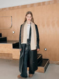 Full body shot of a woman in a black coat and a long colorblock scarf