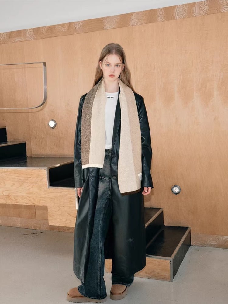 Full body shot of a woman in a black coat and a long colorblock scarf