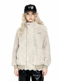 Front view of a woman wearing a beige sherpa fleece bomber jacket with a high collar, ribbed cuffs and hem, and an embroidered logo. She is wearing black leather pants and a black baseball cap with sunglasses.