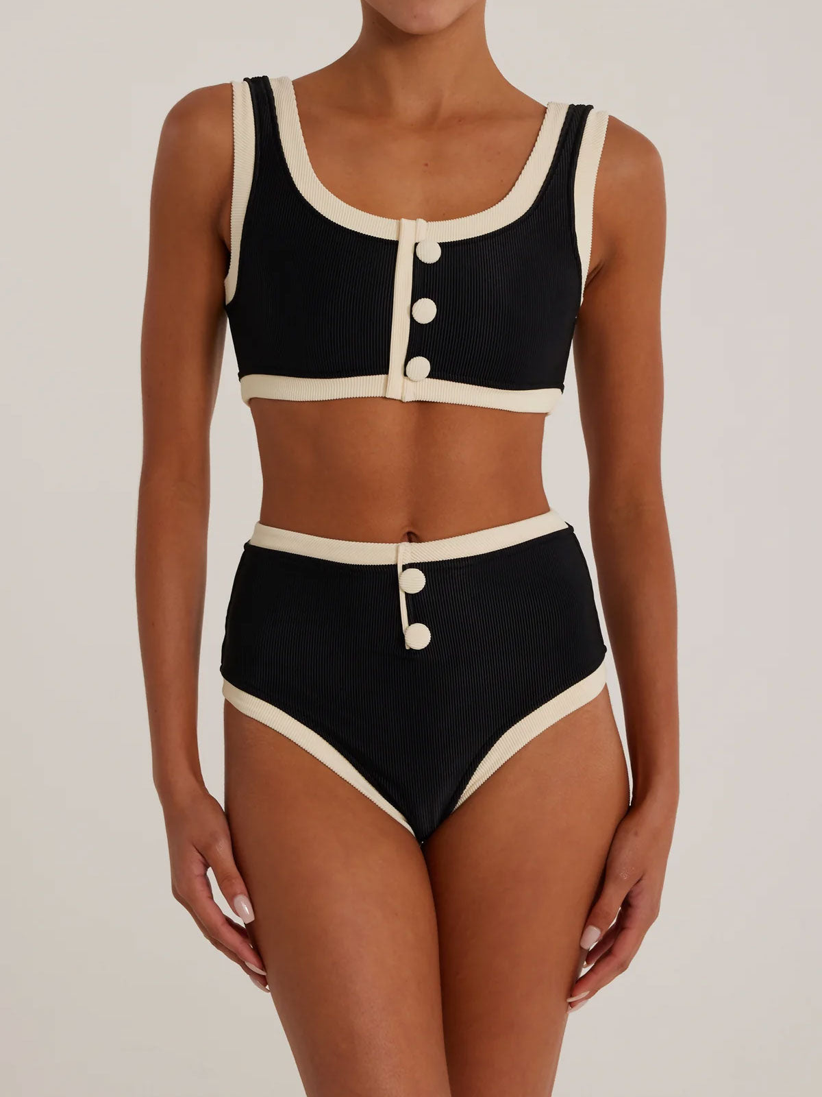 Black ribbed knit bikini top with cream trim and button details, paired with matching high-waisted bikini bottoms.