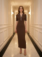 Woman wearing a brown ribbed knit midi dress with white collar trim, standing in a hallway.