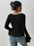 Back view of a woman in a fitted black ribbed knit top with contrast neckline trim.