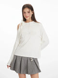 Front detail of a white long-sleeve top featuring a shoulder cut-out with a bow and embroidered graphic.
