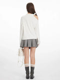 Back view of a woman in a white long-sleeve top and grey pleated skirt, showcasing the full outfit.