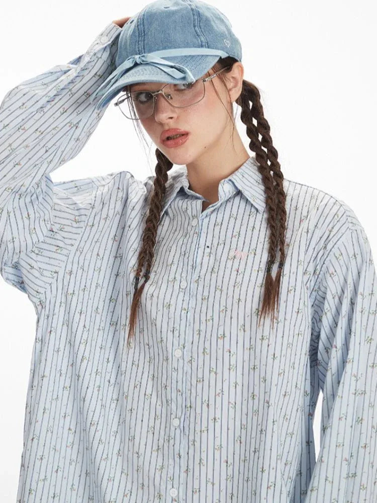 Close-up of a woman's face wearing a light blue pinstripe button-down shirt and a light blue cap, with her hair in braids.