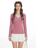 Front view of a woman in a pink long-sleeve top with intricate white lace at the neckline.